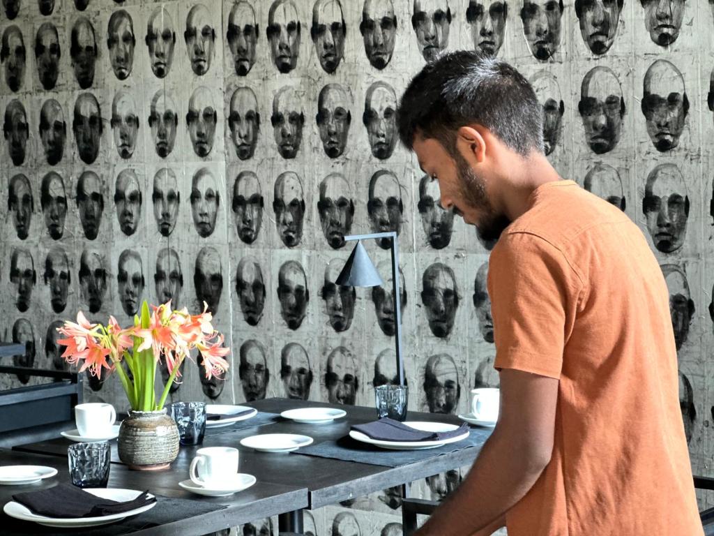 a man standing in front of a table with plates at Saffron Robes Living in Hikkaduwa