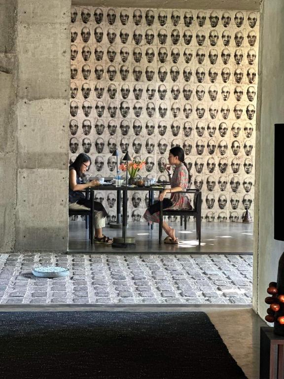 two people sitting at a table in front of a wall at Saffron Robes Living in Hikkaduwa