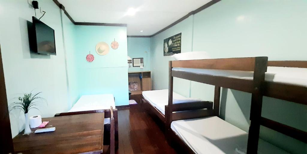 Pinaluyan Guest House في مدينة بورتوبرنسس: غرفة بسريرين بطابقين وتلفزيون