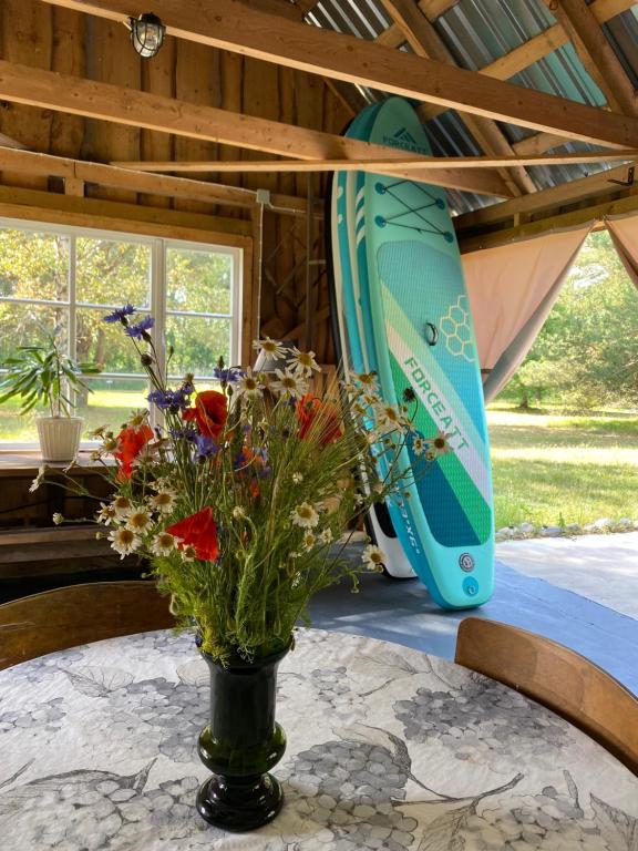 a vase of flowers on a table with a surfboard at Suurkivi Nature Escape in Häädemeeste