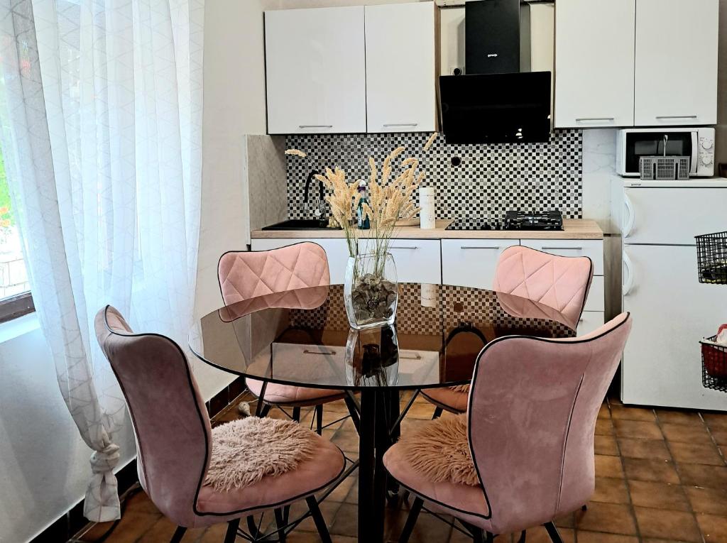 a dining room table with pink chairs and a kitchen at Guest House Tanja in Babino Polje