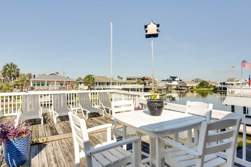 a white table and chairs on a deck with the water at Jamaica Beach Home with Surrounding Water Views! in Galveston