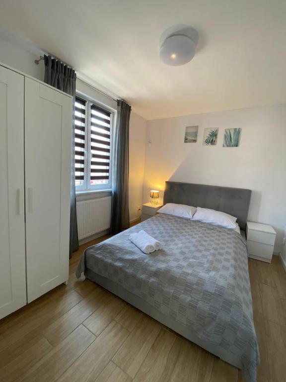 a bedroom with a bed and two windows at Apartament D&M in Mielno