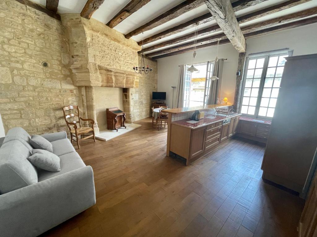 ein großes Wohnzimmer mit einem Sofa und einer Küche in der Unterkunft Appartement de Caractère au Cœur de la Cité Médiévale in Sarlat-la-Canéda
