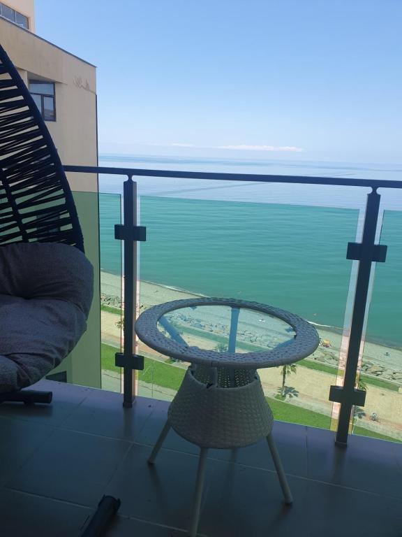 uma mesa e uma cadeira numa varanda com o oceano em The Fresh Wave hotel em Batumi