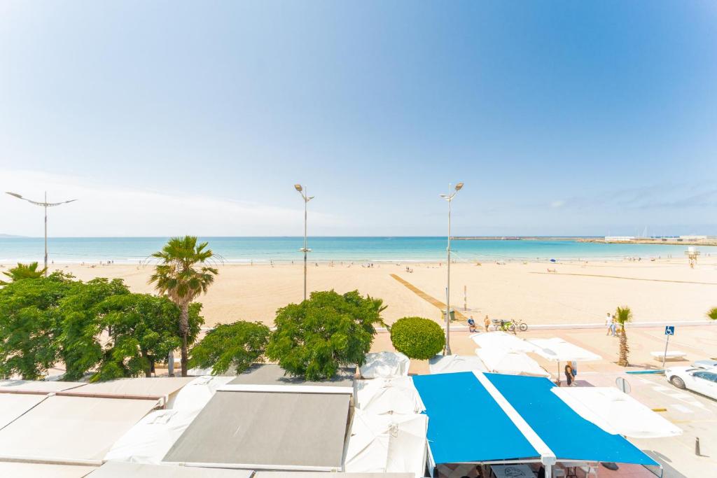 una playa con sombrillas blancas y el océano en Apartamento Estudio Acuario Frente Mar, en Barbate