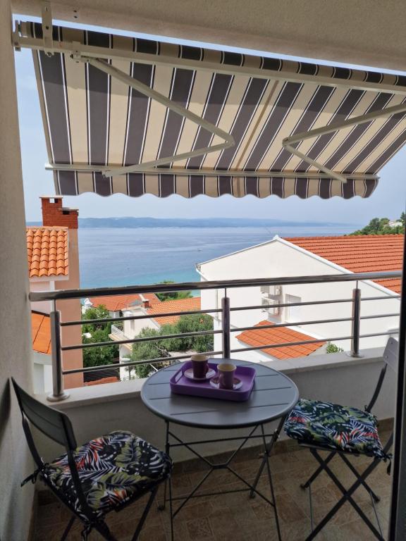 uma mesa e cadeiras numa varanda com vista para o oceano em Apartment NiNa em Baska Voda