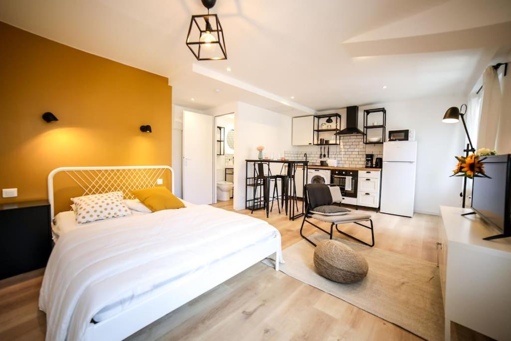 1 dormitorio con 1 cama blanca y cocina en Studio cosy équipé, Centre ville en Orange