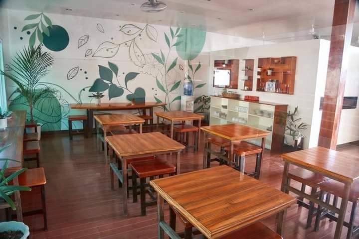 CEBUANA'S TRAVELERS INN Coron في كورون: مطعم بطاولات وكراسي خشبية في الغرفة