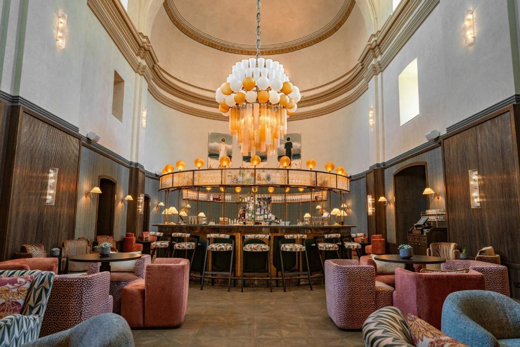 a large lobby with a chandelier and a bar at Stradom House, Autograph Collection in Krakow