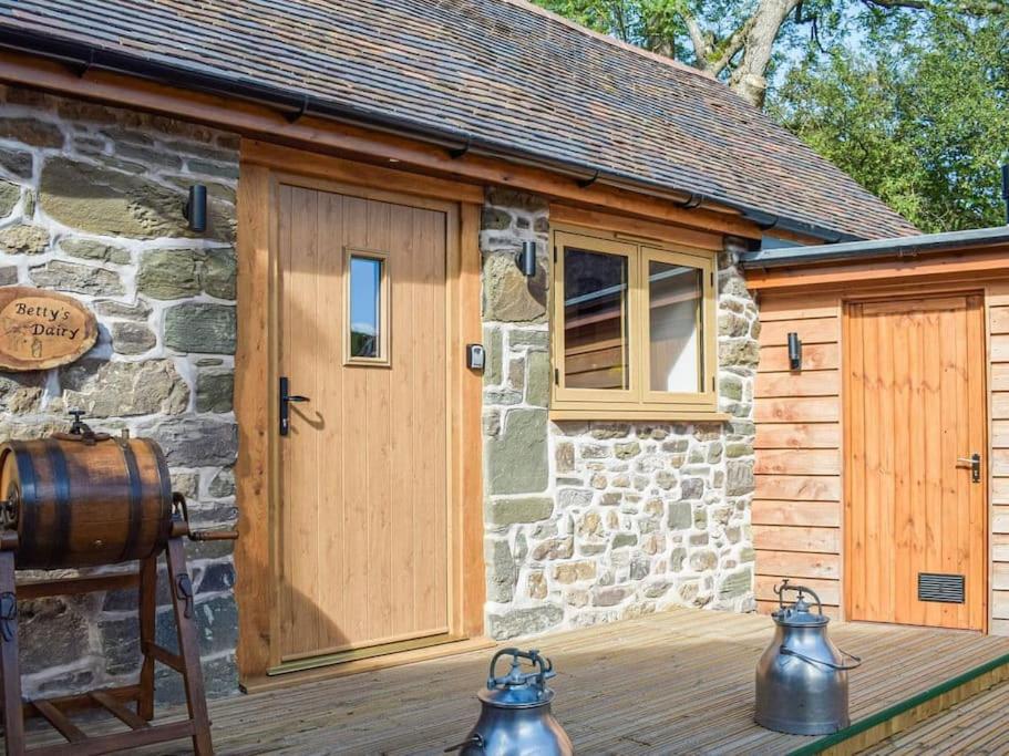 a stone cottage with a wooden door and a barrel at Stunning cottage nestled under the Longmynd Hills. in Church Stretton