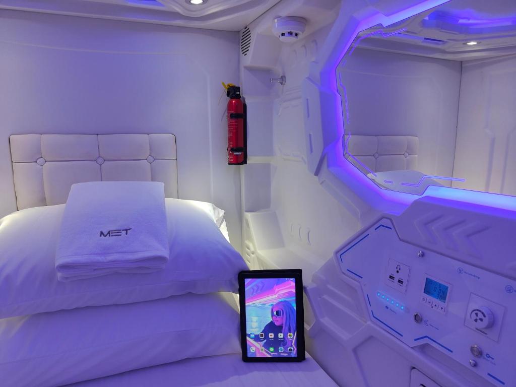 ein Zimmer mit einem Bett mit einem Tablet daneben in der Unterkunft Met A Space Pod @Phrom Phong in Bangkok