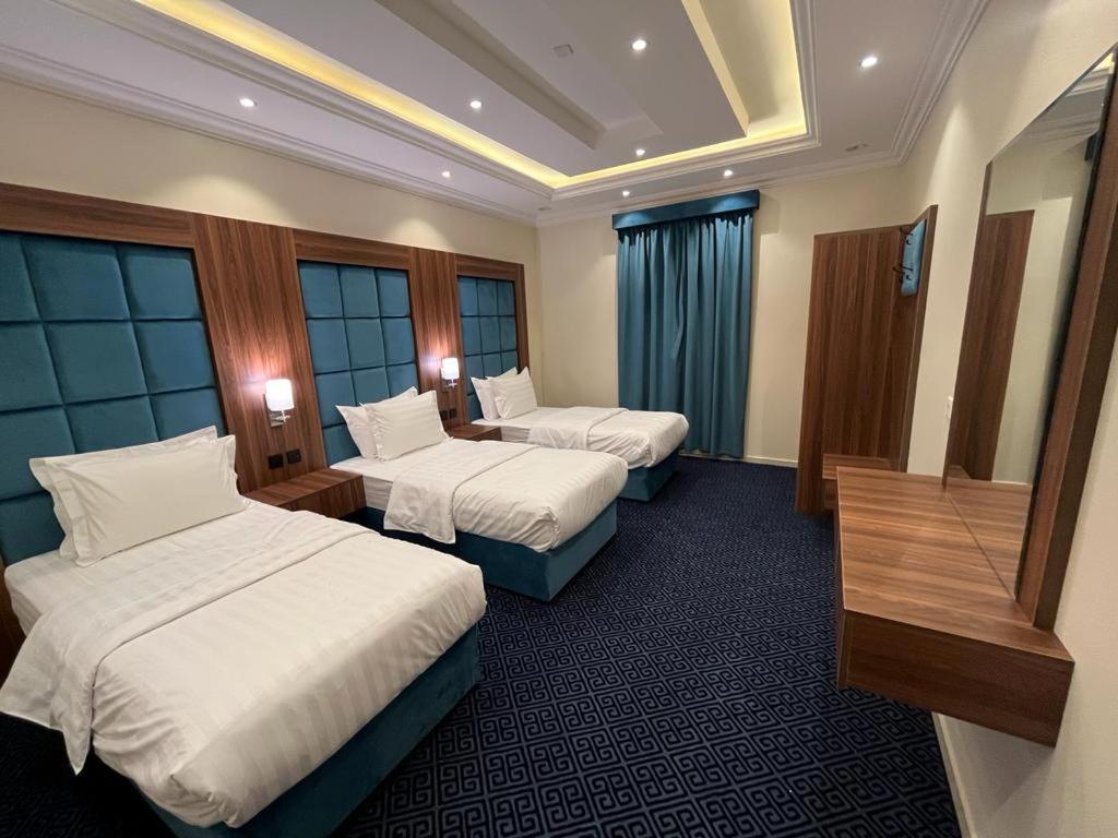 um quarto de hotel com duas camas e uma mesa em مساكن الراحة em Abha