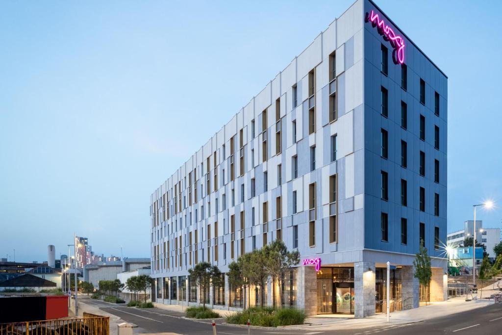 a white building with a pink hotel sign on it at Moxy Plymouth in Plymouth