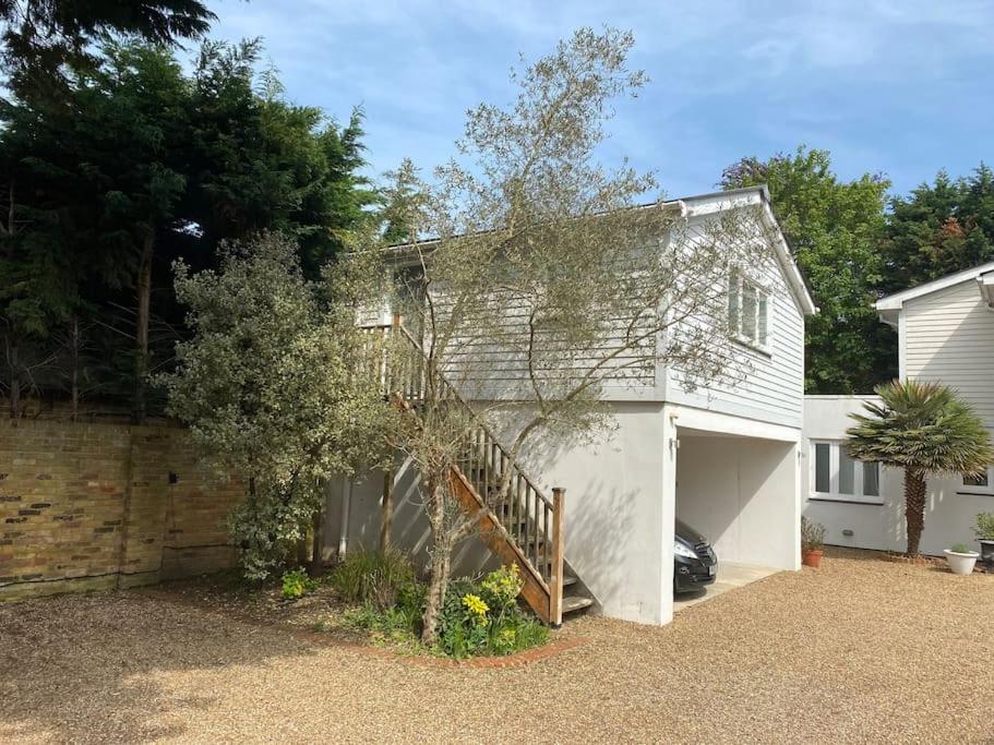 a white house with a garage and a staircase at 2 person studio flat near Richmond Park in Strawberry Hill