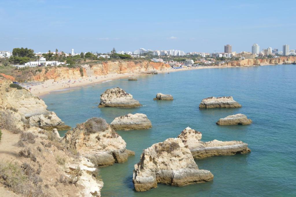 a group of rocks in the water near a beach at 3 Bedroom Apartment with pool Alvor in Alvor