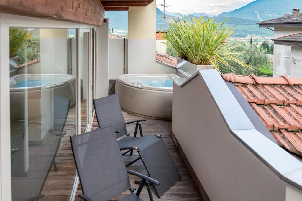 einen Balkon mit einer Badewanne, Stühlen und einem Tisch in der Unterkunft Charming Loft - Private Hot Tub & Free Parking in Riva del Garda