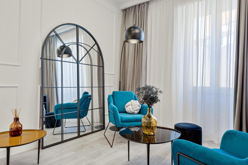 ein Wohnzimmer mit blauen Stühlen, einem Tisch und einem Spiegel in der Unterkunft EC Luxury Rooms in Riomaggiore