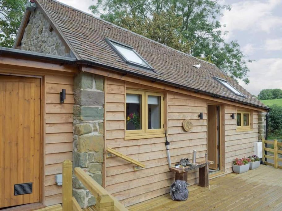 eine kleine Holzhütte mit einer Holzterrasse in der Unterkunft Cosy and quiet one bed barn conversion. in Church Stretton