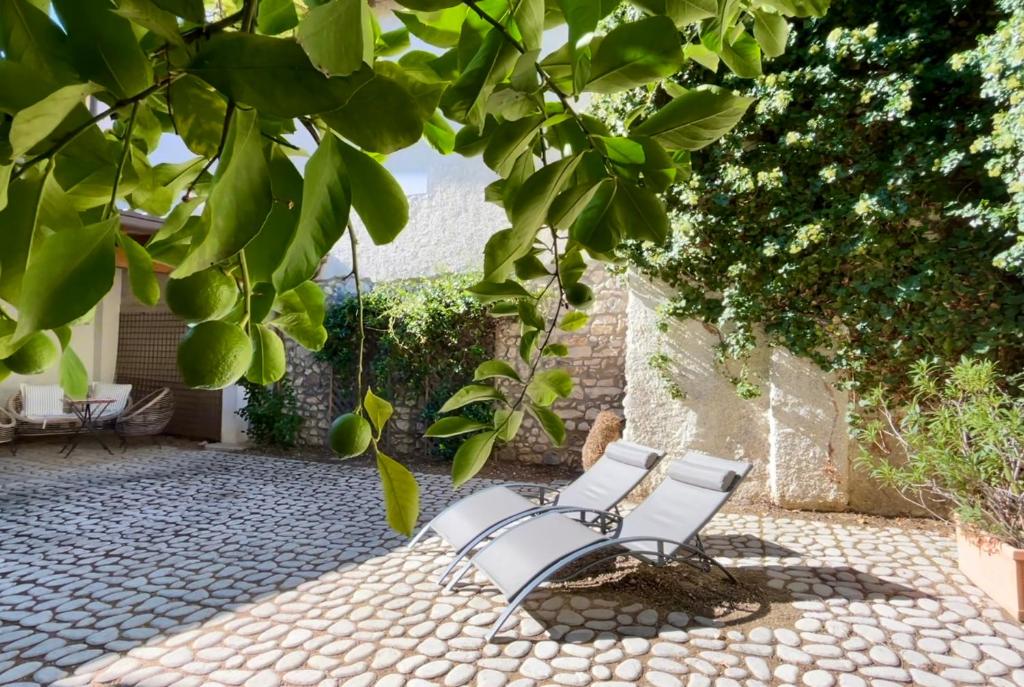 twee witte stoelen op een patio onder een boom bij Borgo dei Sogni - Deluxe Apartment - Lago di Garda in San Felice del Benaco