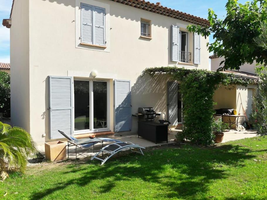 une maison blanche avec une chaise et une table dans la cour dans l'établissement Bastide au pieds des alpilles St remy de Provence piscine partagée dans résidence, à Saint-Rémy-de-Provence