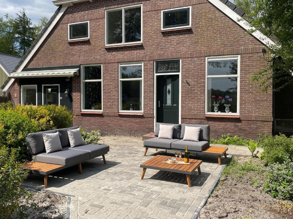 a patio with couches and tables in front of a building at Vacation home in Schoonloo with terrace in Schoonloo