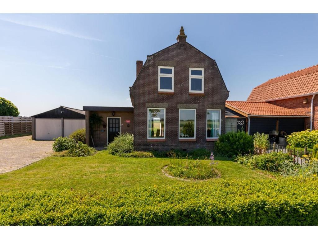 une grande maison en briques avec une cour d'herbe dans l'établissement characteristic house in a rural location in the village of Zuidzande with garden, à Zuidzande