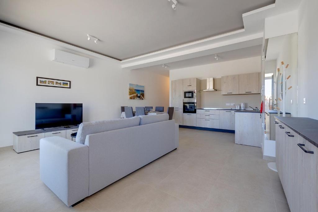 a living room with white furniture and a kitchen at Luxury Maisonette in a Tranquil and Central Area in St. Julianʼs