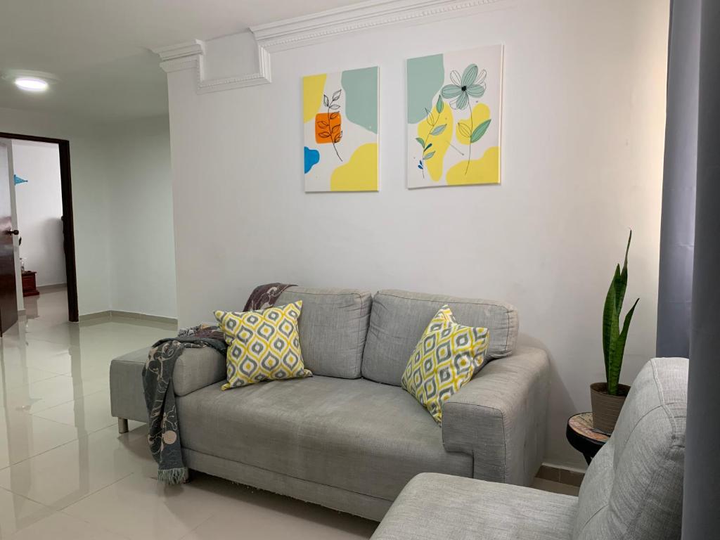 sala de estar con sofá gris y pinturas en la pared en Habitación en apartamento compartido al frente del cc Unico, en Barranquilla
