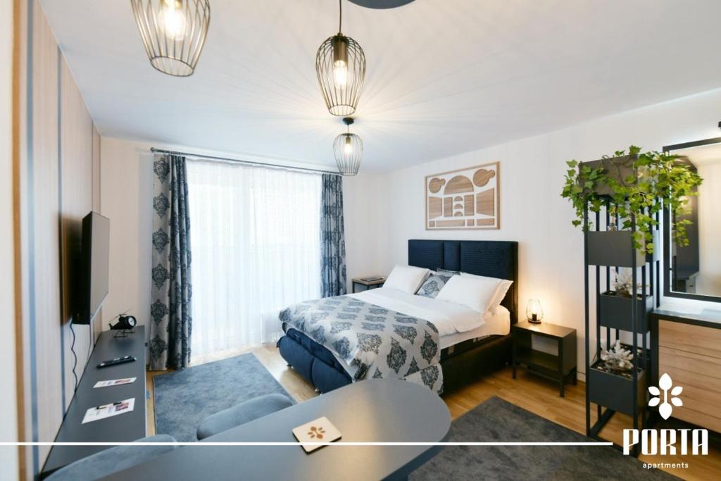 a bedroom with a bed and a table in a room at Porta Apartman Sarajevo in Sarajevo