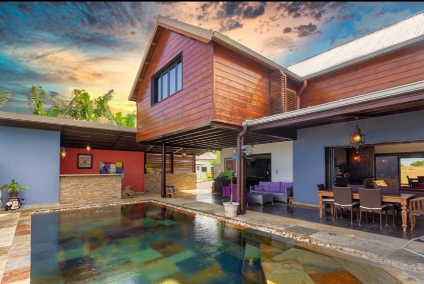 a house with a swimming pool in front of a house at Villa Hermès Chambre bleue océan in Saint-Pierre