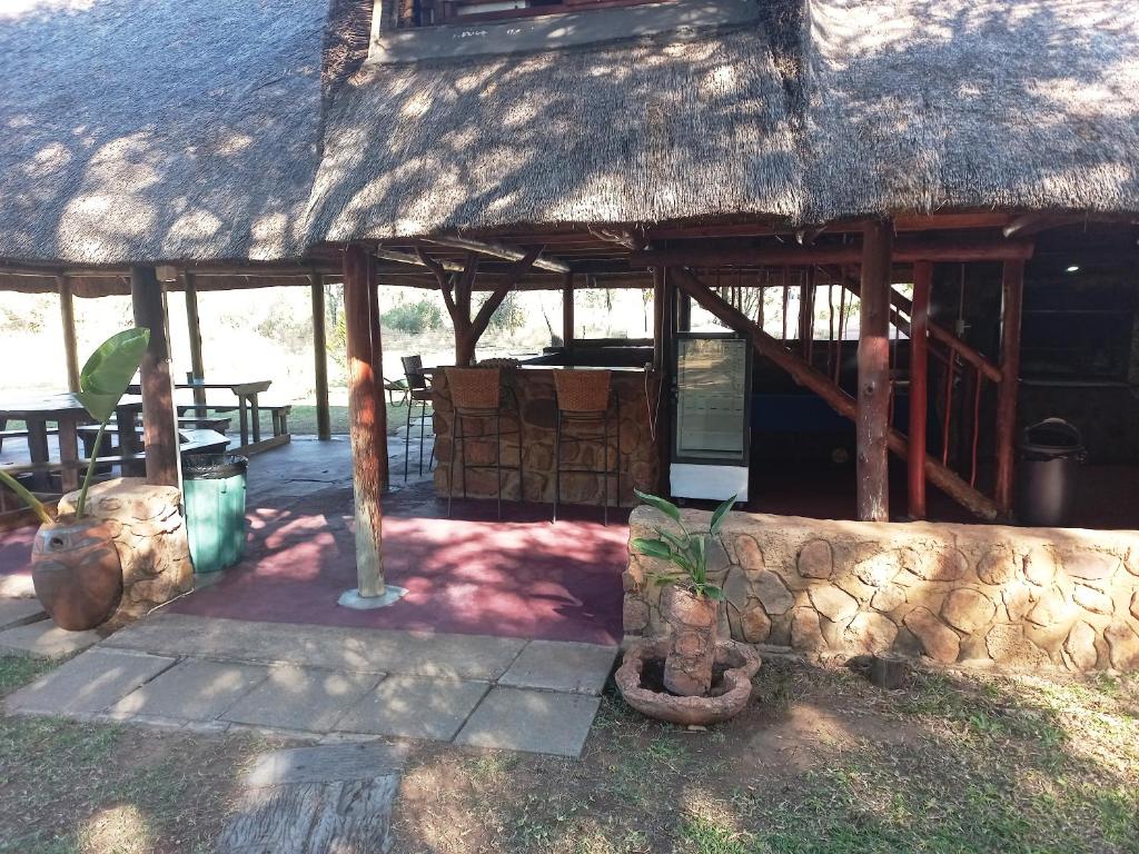 a building with a thatched roof and a stone wall at Thekwane Holiday House in Klipdrift