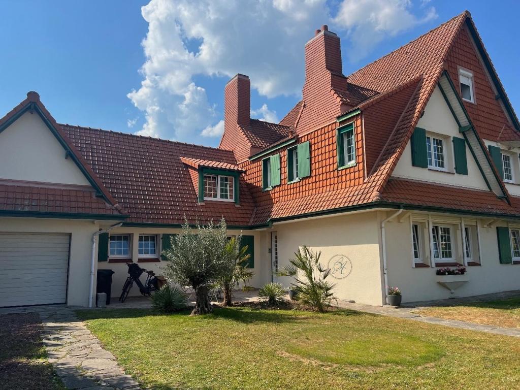 une maison avec un toit rouge dans l'établissement STUDIO Villa vacances, à Le Touquet-Paris-Plage