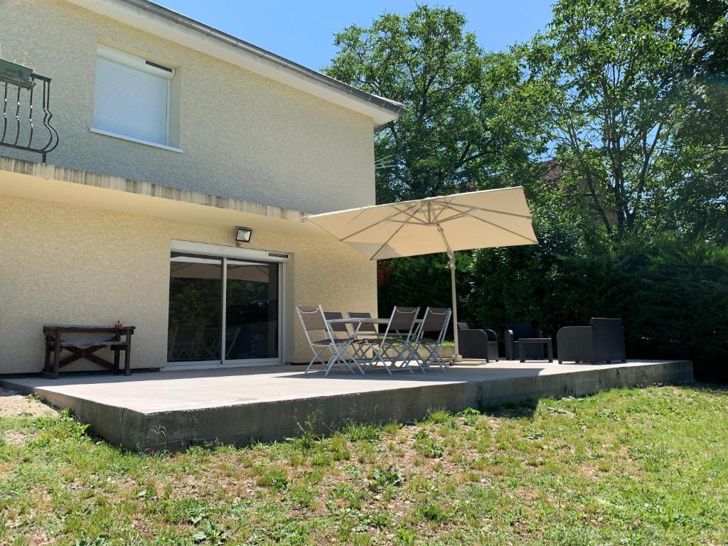 een patio met een tafel en stoelen en een parasol bij Dépendance chaleureuse et calme in Champagneux