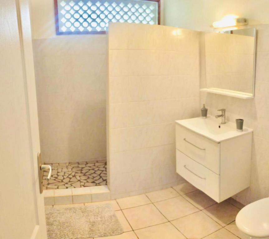 a white bathroom with a sink and a shower at Maison du Lac - jusqu'à 4 personnes in Rémire-Camp