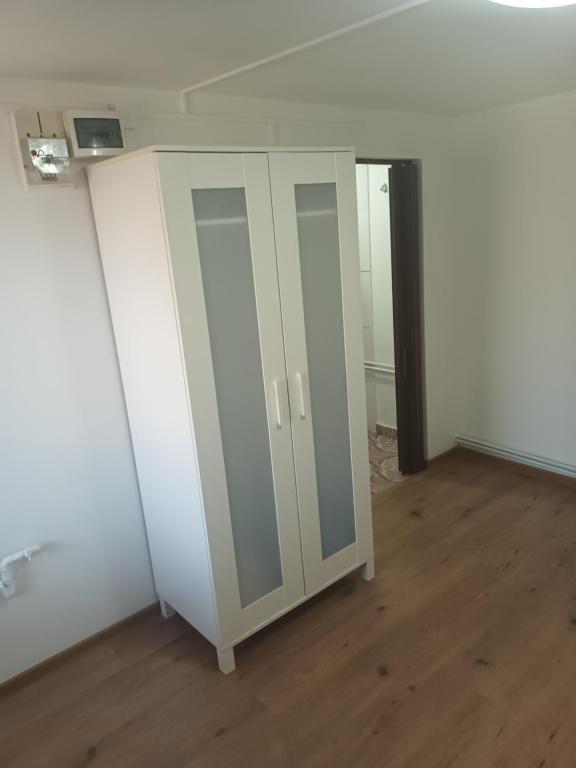 een lege kamer met witte kasten en houten vloeren bij Camera con bagno in Ploieşti