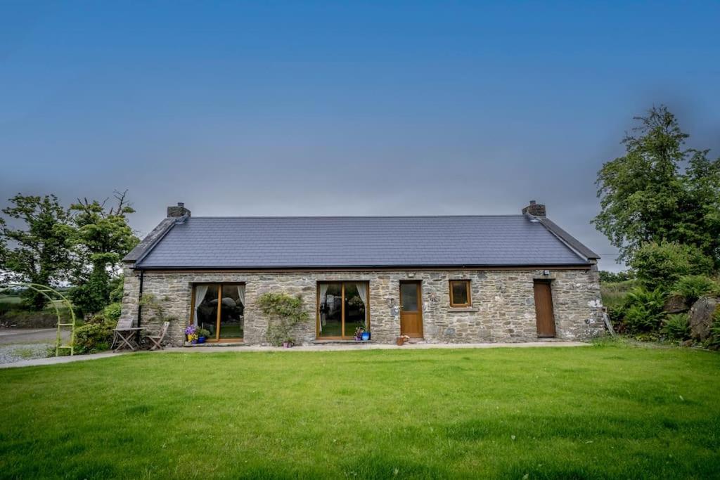 una casa de piedra con un gran patio verde en Water and Wildwood - The Bothy Cottage en Muff