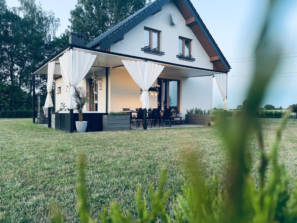 Casa blanca con mesa y sillas en un campo en Żuławski Chillout, 