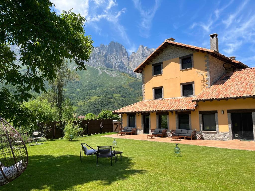 a house with a yard with a mountain in the background at Hotel Eigón in Posada de Valdeón