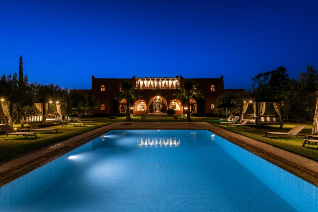 una piscina di fronte a una casa di notte di Riad Al Riadinou ad Aghmat