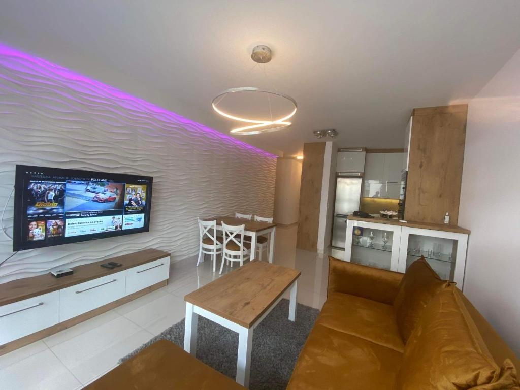 uma sala de estar com um sofá e uma televisão na parede em Apartament VIP em Cracóvia