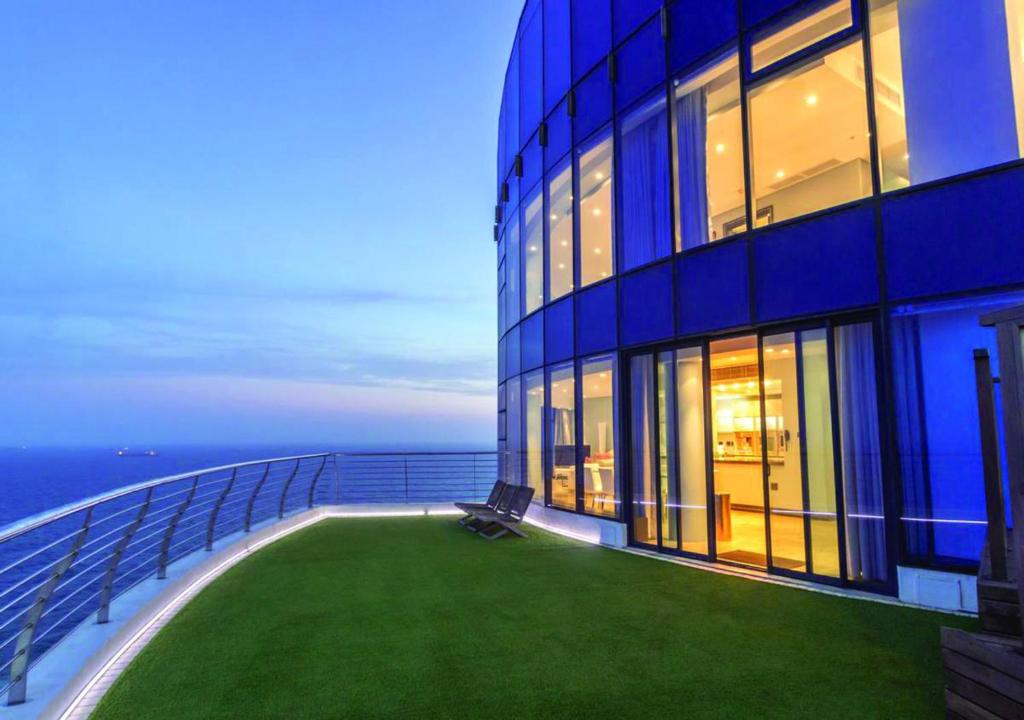 a blue building with a green lawn in front of it at Pearls of Umhlanga Multi-Story Penthouse in Durban