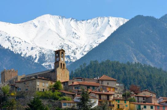 une ville avec une tour d'horloge en face d'une montagne dans l'établissement F4 VERNET LES BAINS, à Vernet-les-Bains