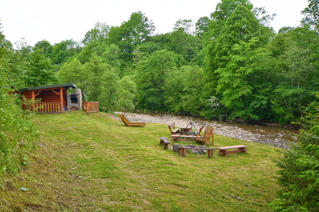 a group of picnic tables in a field next to a river at Noclegi u Kanara in Lutowiska