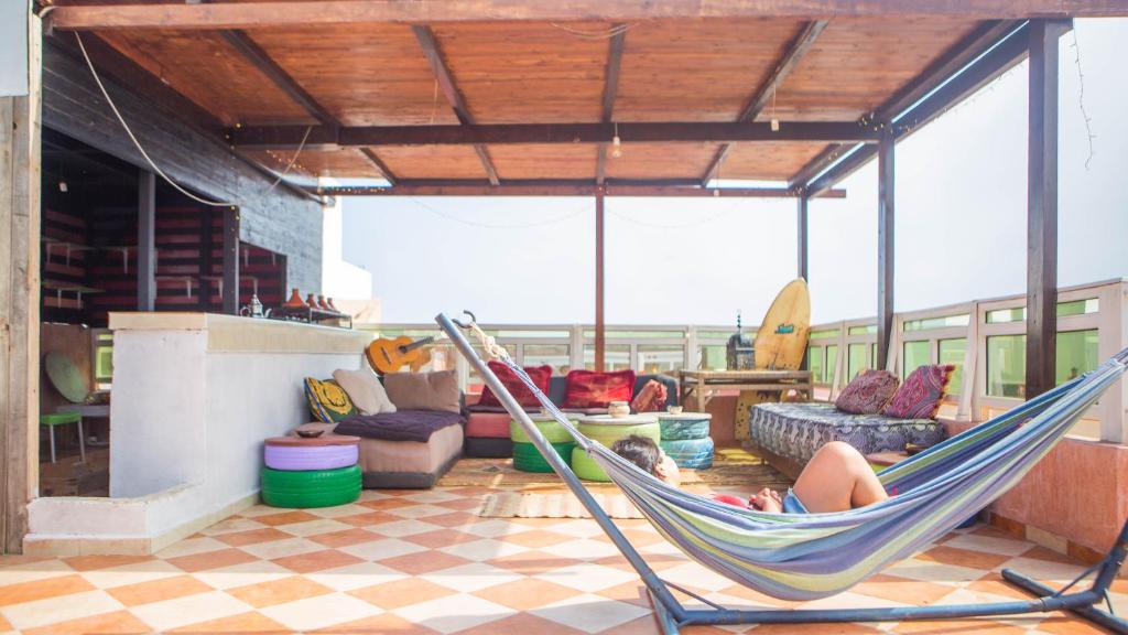 a person sitting in a hammock in a living room at Mubaradise Surf Hostel in Imsouane
