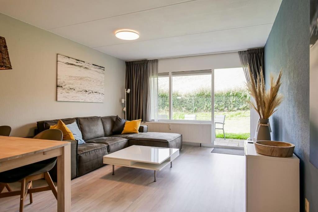 een woonkamer met een bank en een tafel bij Beach Appartement 10 - Aan de duinen, Callantsoog aan Zee in Callantsoog