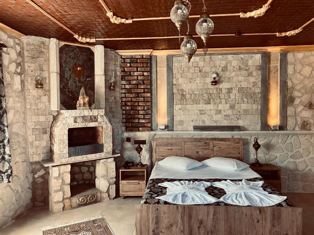 a bedroom with a bed and a brick wall at Aysultan Stone House in Uçhisar