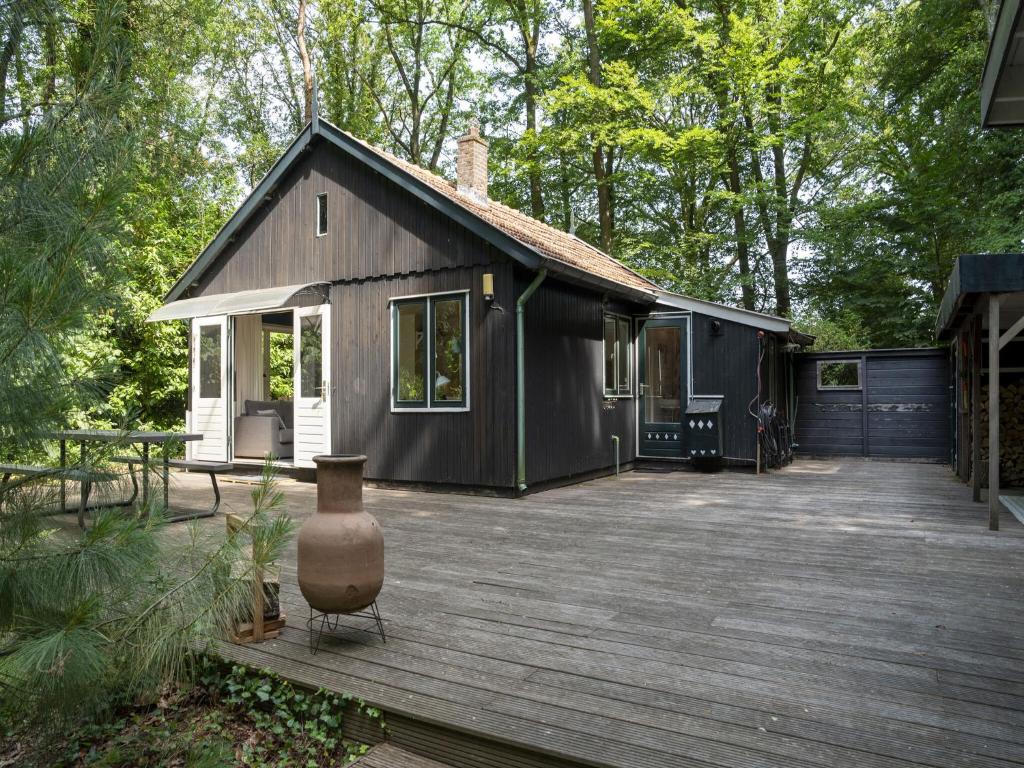 una pequeña casa negra con terraza de madera en Tranquil holiday home in Epse with sauna en Epse