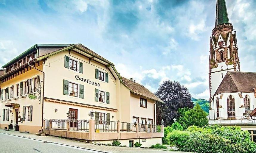 um edifício com uma torre de relógio ao lado de uma igreja em Hotel Kirchbühl em Schönau im Schwarzwald