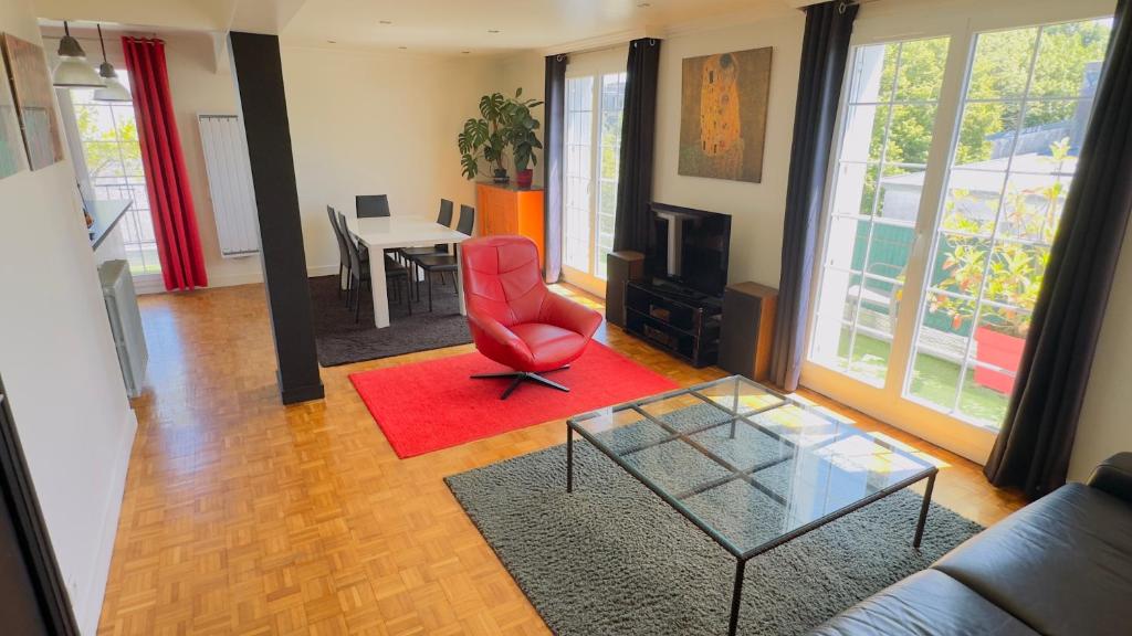 un salon avec une chaise rouge et une table dans l'établissement Spacieux Lumineux Confort Terrasse, à Brest